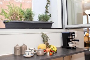A kitchen counter with a coffee maker, tea set, fruit, and potted plants. - The Prestige Acropolis Penthouse - Breathtaking Parthenon View in Plaka (Athina)