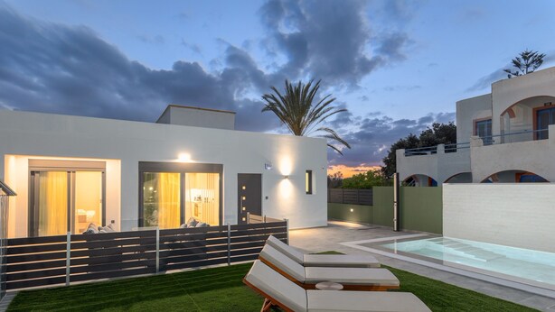 A modern house with a swimming pool, a well-maintained lawn, and a patio with lounge chairs. - Potame Suite by Estia Pool View (Hersonissos)
