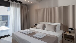 A modern hotel room with a large bed, a bedside table with a lamp, and a view of the outdoors through a large window. - Potame Suite by Estia Pool View (Hersonissos)