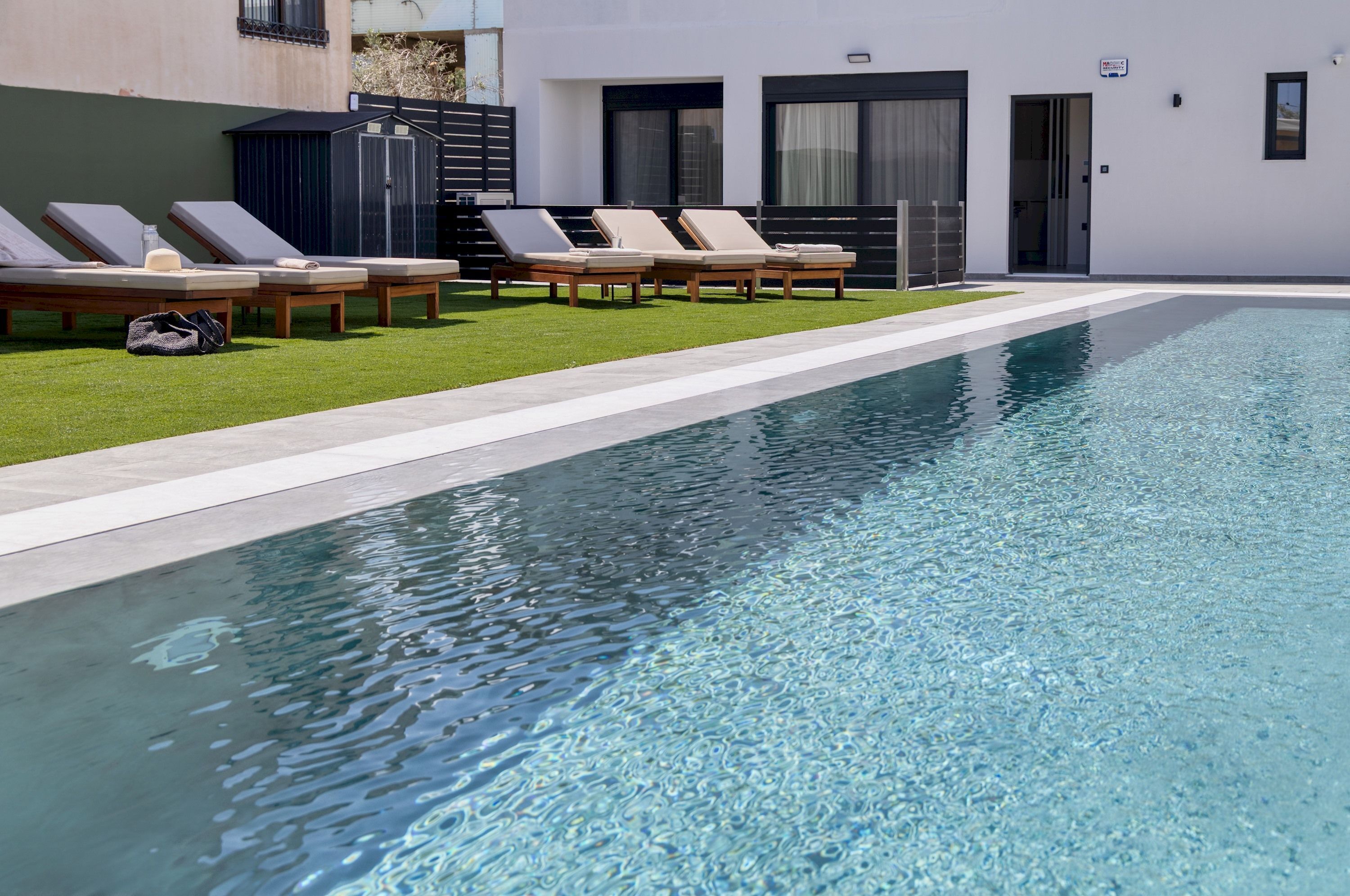 A swimming pool with lounge chairs and a small garden area.