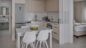A modern kitchen with light wood cabinets, a white dining table with chairs, and a breakfast bar. - Potame Suite by Estia Pool View (Hersonissos)