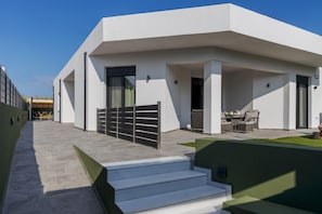 A modern building with a flat roof, a covered outdoor seating area, and a gated entrance.