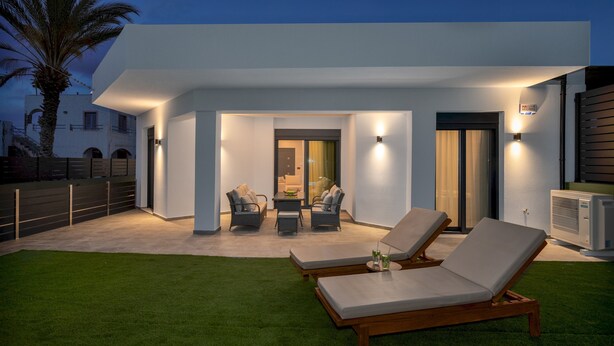 A modern outdoor patio with two lounge chairs, a table, and a sofa.
