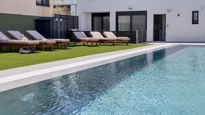 A swimming pool with lounge chairs and a small garden area.