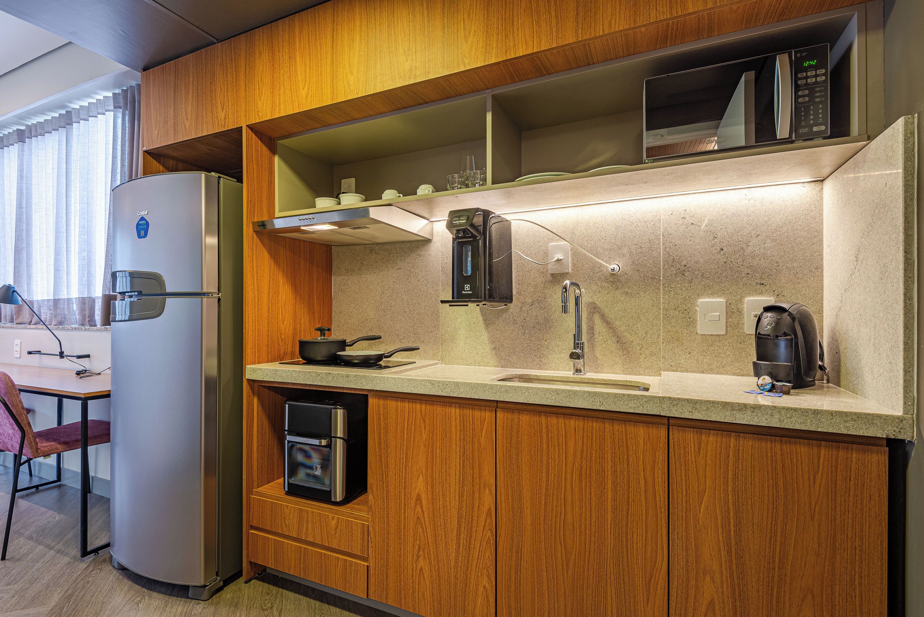 Cocina compacta con microondas integrado, cafetera y horno pequeño.