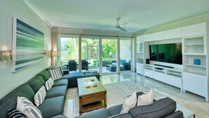 A modern living room with a sectional sofa, a coffee table, and a flat-screen TV.
