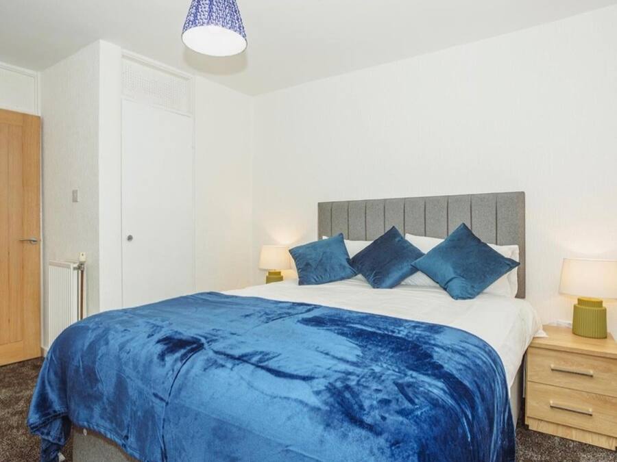 Quarto com cama, mesas de cabeceira, luminária e luminária pendente.