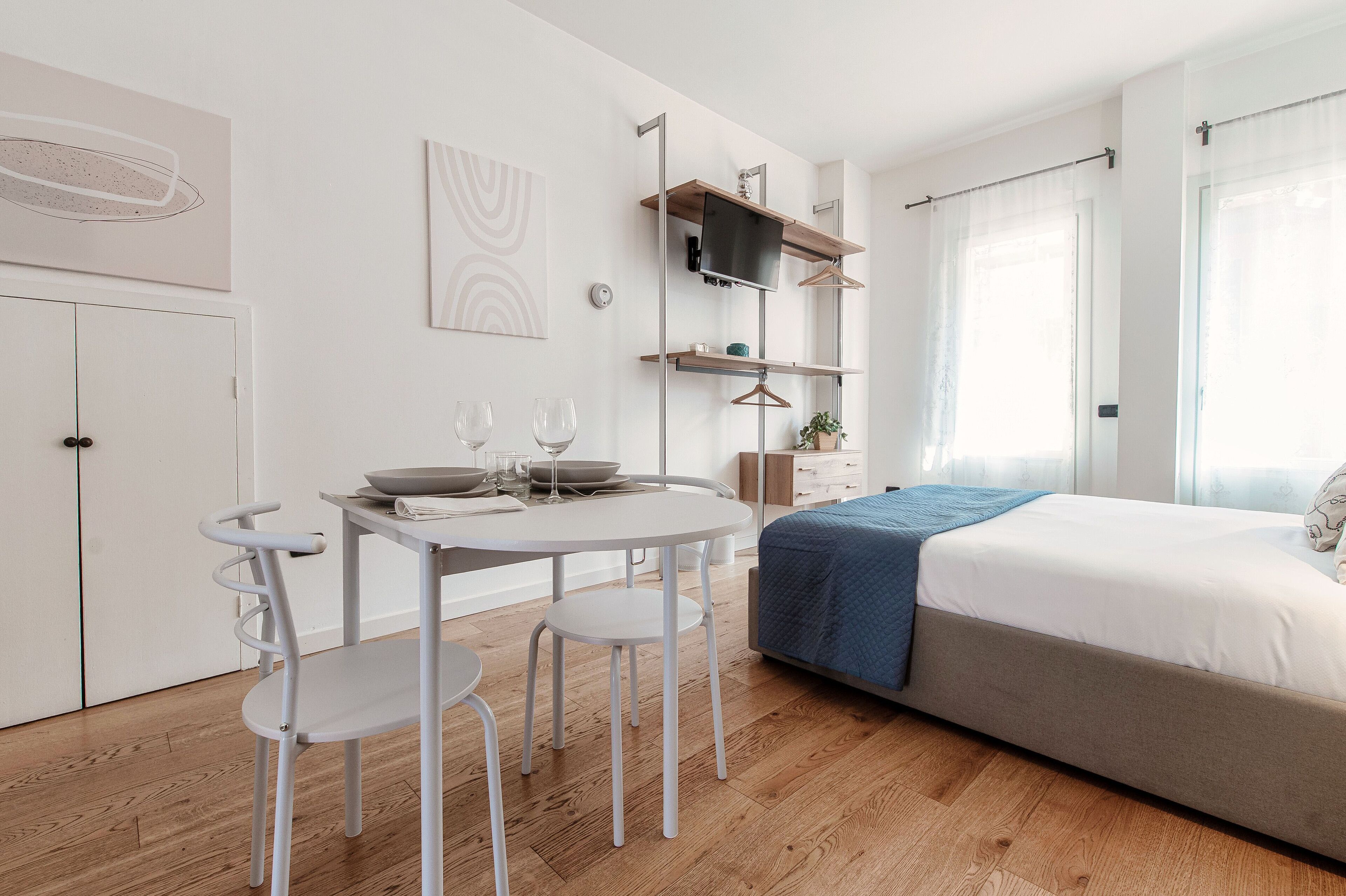 A modern bedroom with a bed, bedside tables, a TV, and a window with curtains.