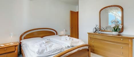 Une chambre avec un lit en bois, une commode, un miroir et un vélo à l’arrière-plan.