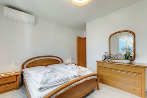 A bedroom with a wooden bed, a dresser, a mirror, and a bicycle in the background.