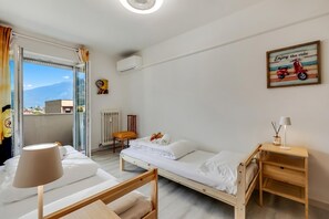 Un lit simple avec un cadre en bois, une table de chevet avec une lampe, un radiateur et une fenêtre avec des rideaux.