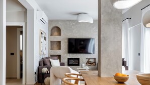 Una sala moderna con una mesa de comedor de madera, un sofá y un televisor montado en la pared.