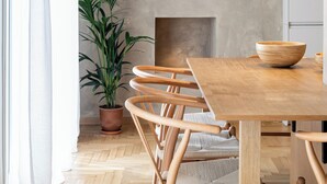 Un comedor moderno con una mesa y sillas de madera, una planta en maceta y una pared texturizada con estantes integrados.
