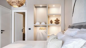 Un dormitorio con una cama grande, un armario con estantes y una lámpara colgante.
