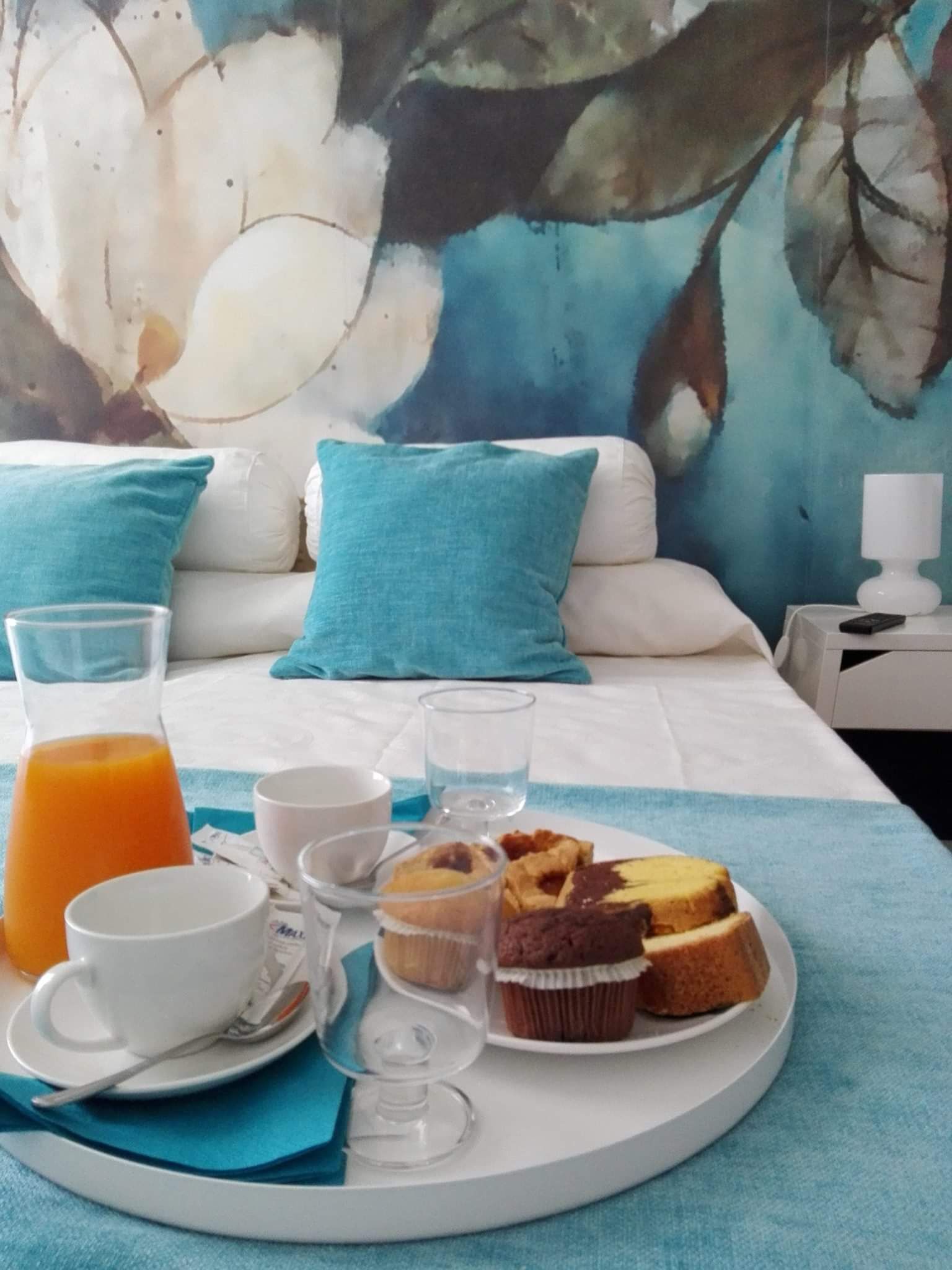 A breakfast setup on a bed with a painting in the background.