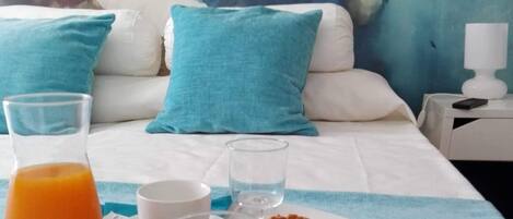 A breakfast setup on a bed with a painting in the background.