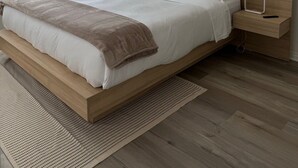 Une chambre moderne avec un grand lit, une table de chevet avec une lampe et deux œuvres d’art encadrées accrochées au mur.