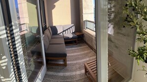 Un balcon avec un canapé, une petite table et un tapis à motifs.