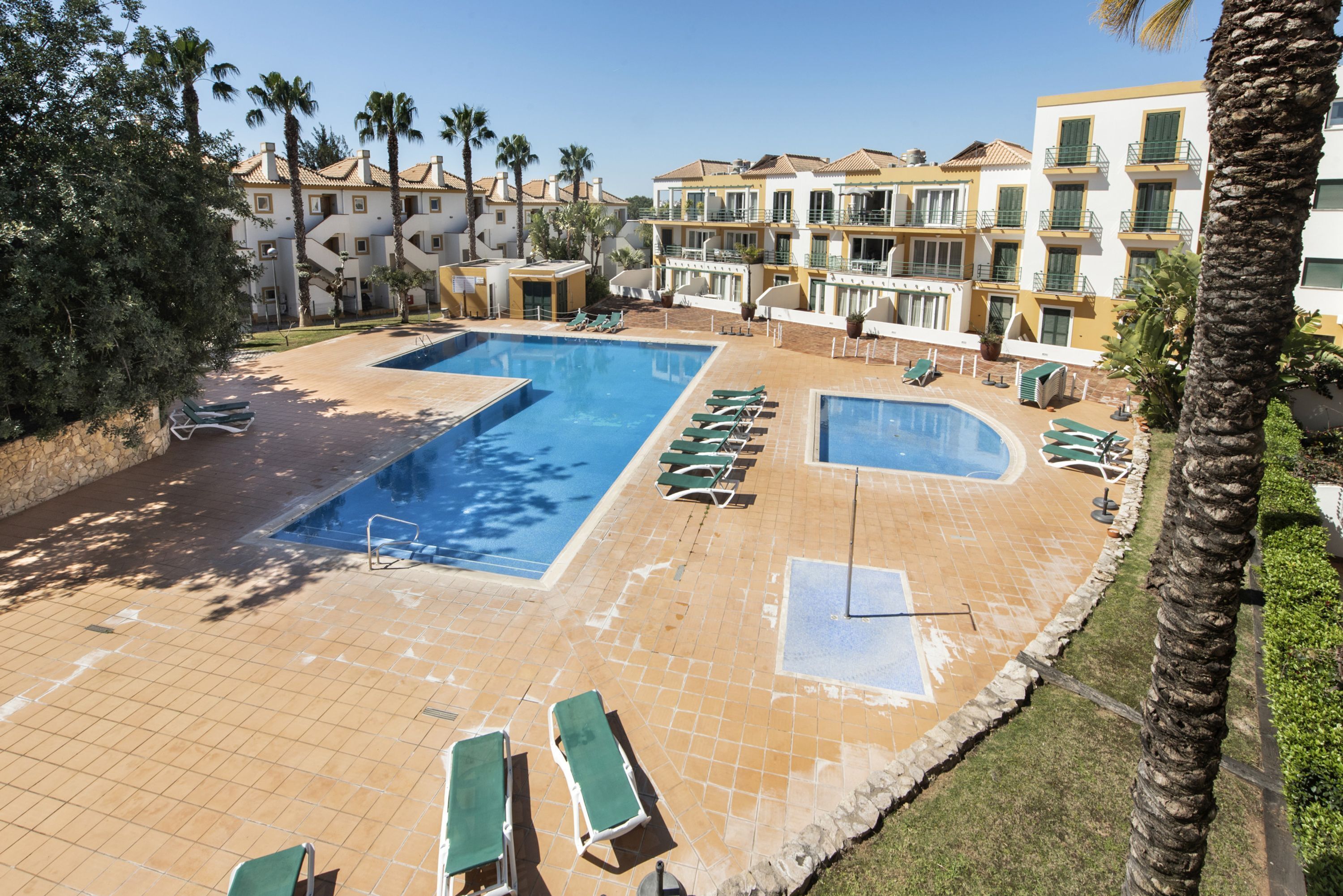 A resort pool area with multiple sun loungers and a large swimming pool.