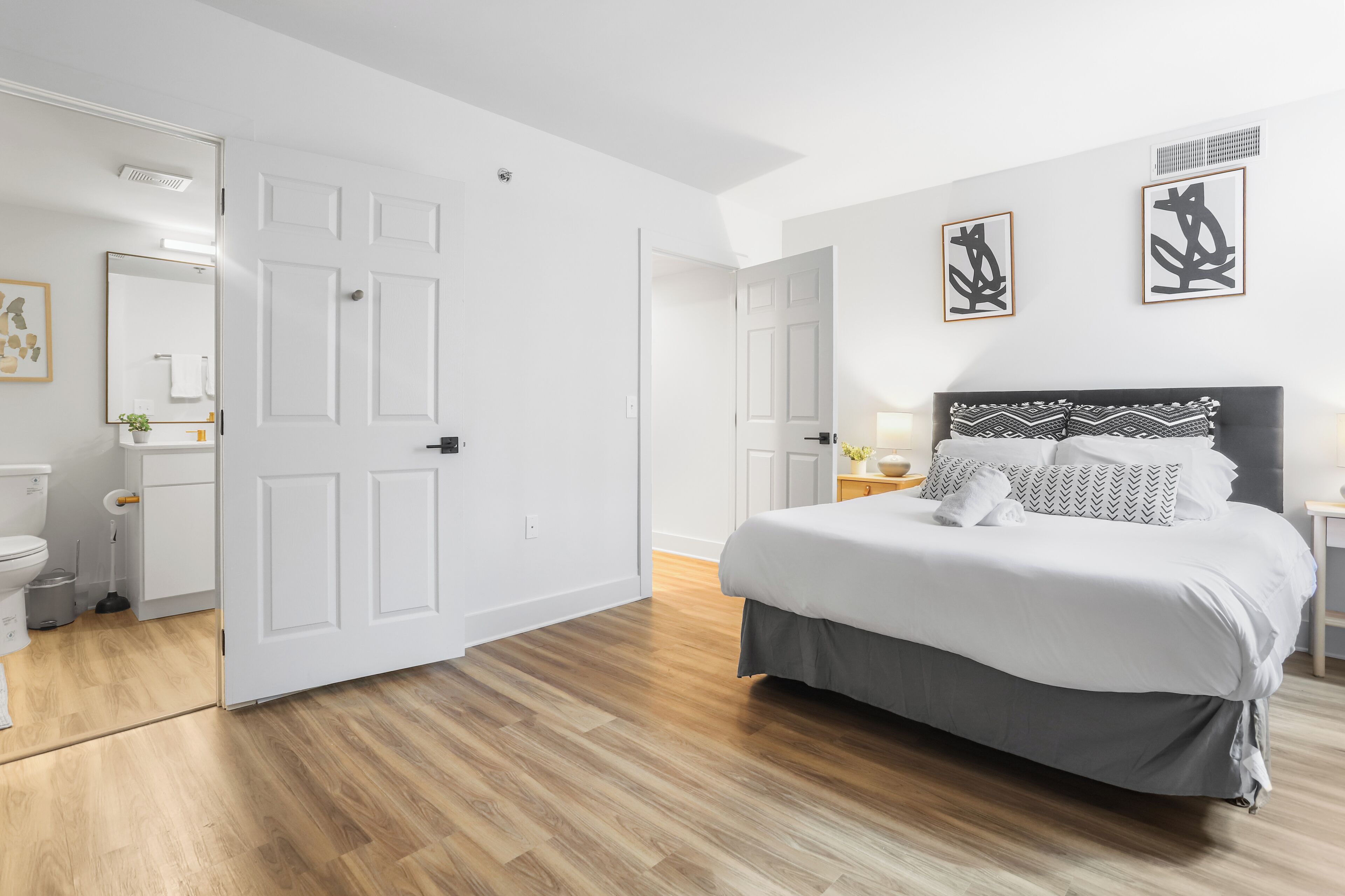 A modern bedroom with a large bed, a bedside table, a nightstand, and a wardrobe.