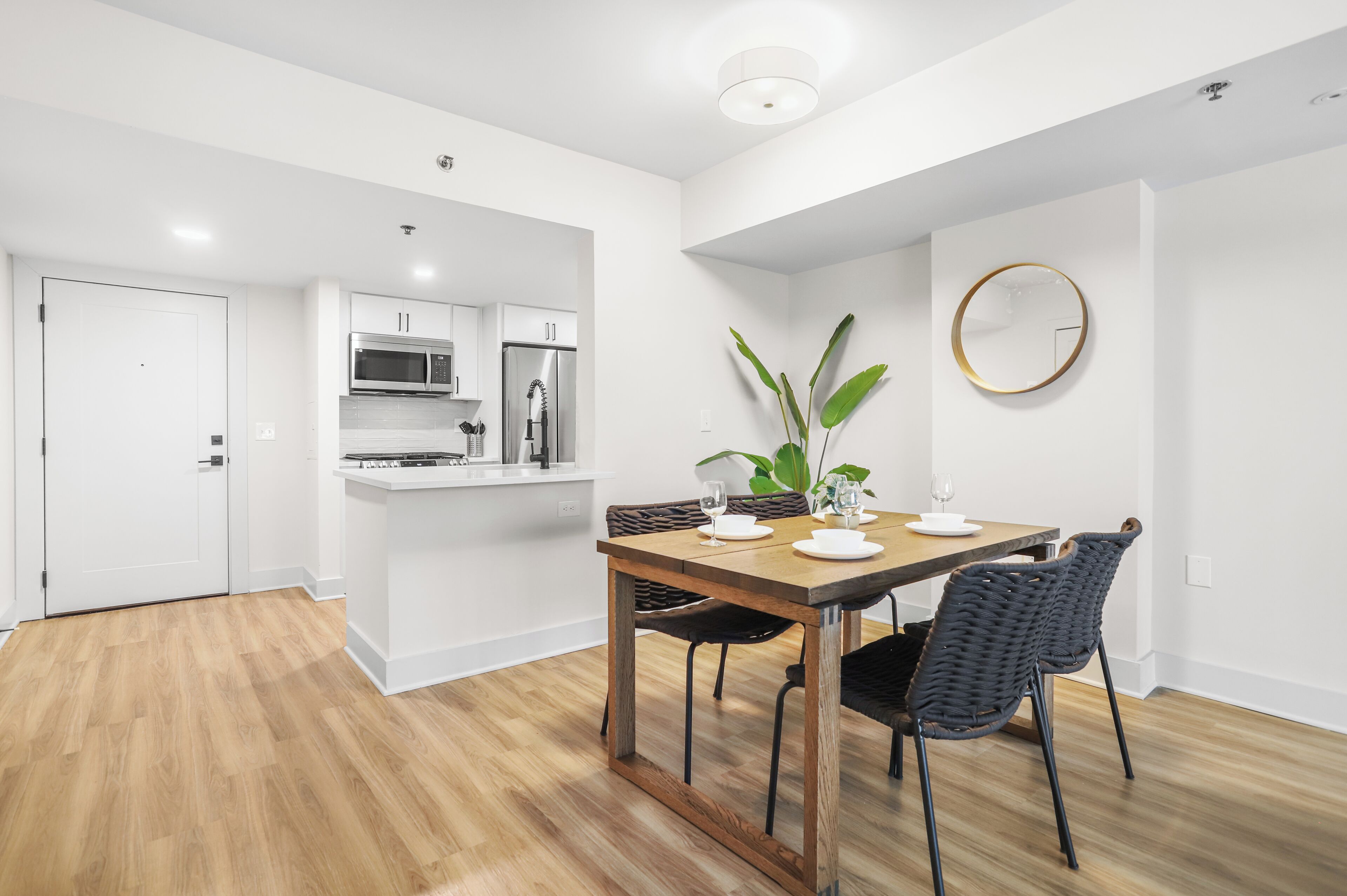 A modern kitchen with white cabinets, a stainless steel microwave, and a refrigerator.
