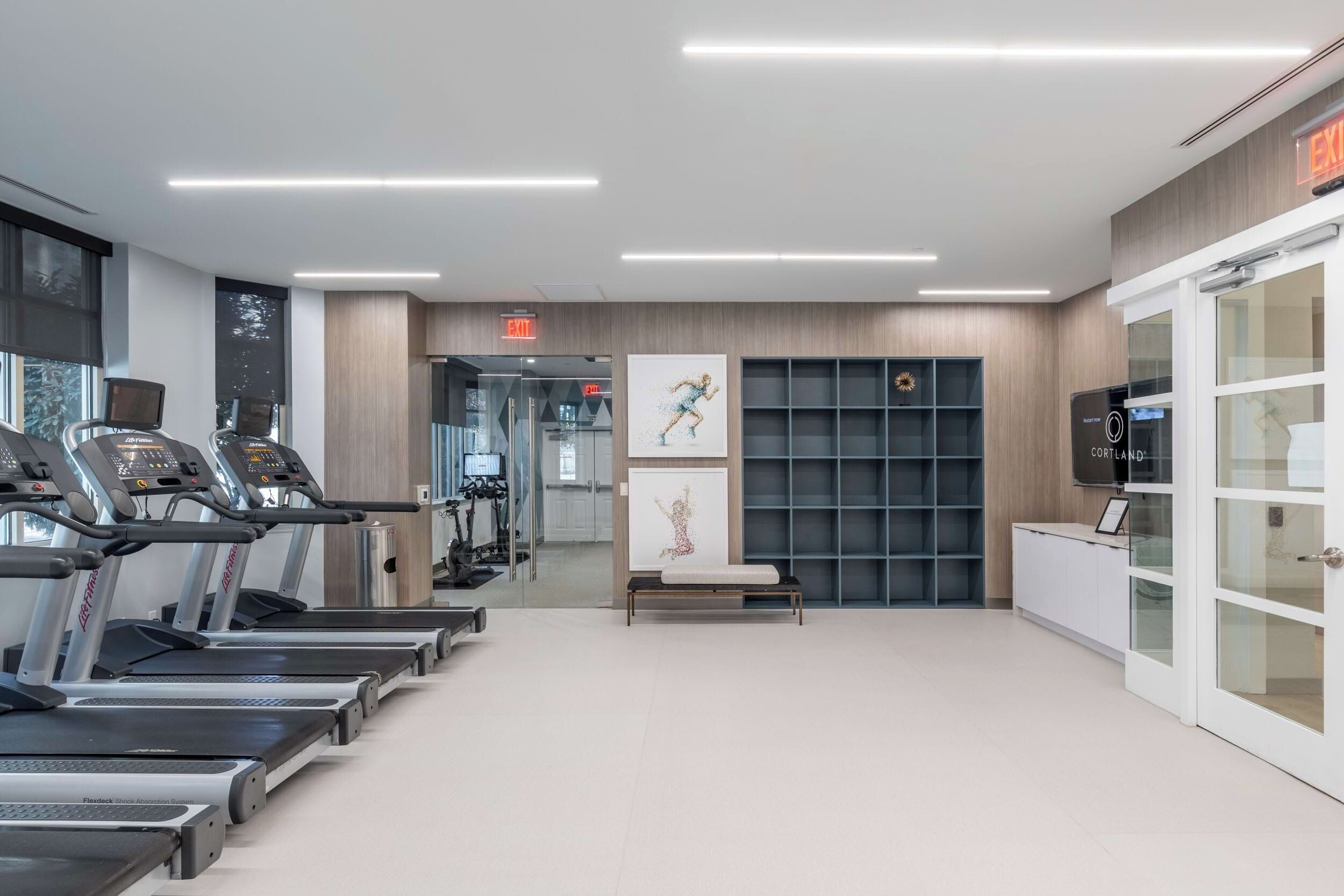 A modern gym with treadmills, exercise equipment, and artwork.