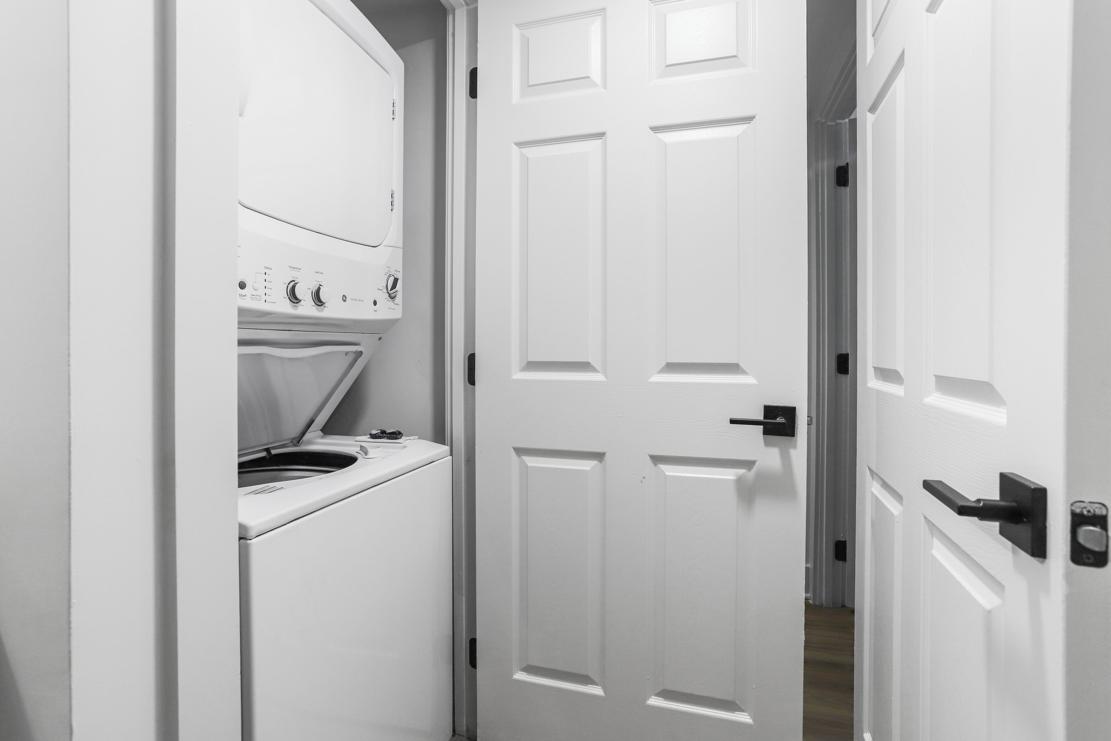 A narrow hallway with a white door and a laundry machine.