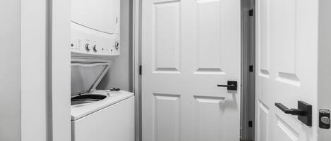 A narrow hallway with a white door and a laundry machine.