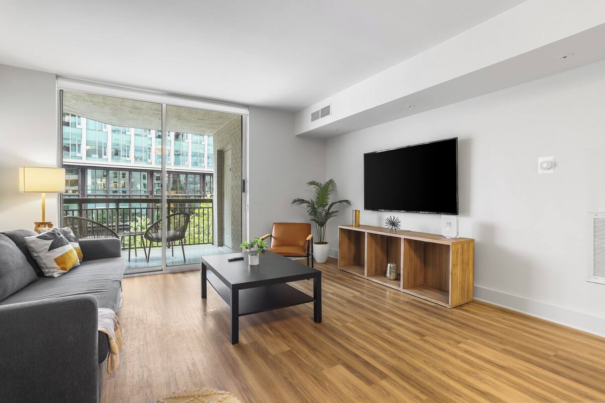 A modern living room with a sofa, coffee table, TV, and a balcony with chairs.