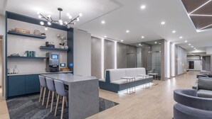 Un interior moderno con área de cocina, asientos y un separador de vidrio.