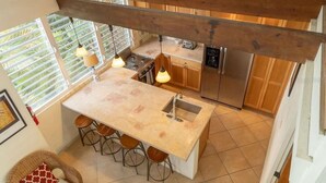 A kitchen with a large island, bar stools, a built-in oven, and a refrigerator.