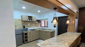 A modern kitchen with a central island, wooden cabinets, and a built-in oven. - Yellow Door Aparment (Abuja)