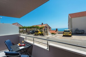 Ein Balkon mit Tisch und Stühlen mit Blick auf eine Straße, auf der Autos geparkt und Häuser zu sehen sind.