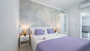 A modern bedroom with a large bed, two bedside tables with lamps, a wardrobe, and a grey textured wall. - Charming 1-bedroom apartment in lovely Cavtat (Cavtat)