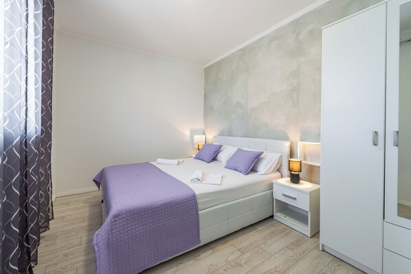 Ein ordentlich eingerichtetes Schlafzimmer mit einem Bett, Nachttischen und einem Kleiderschrank.