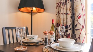A dining table set with plates, bowls, glasses, and a bottle of wine. - Rose Cottage (Nottingham)