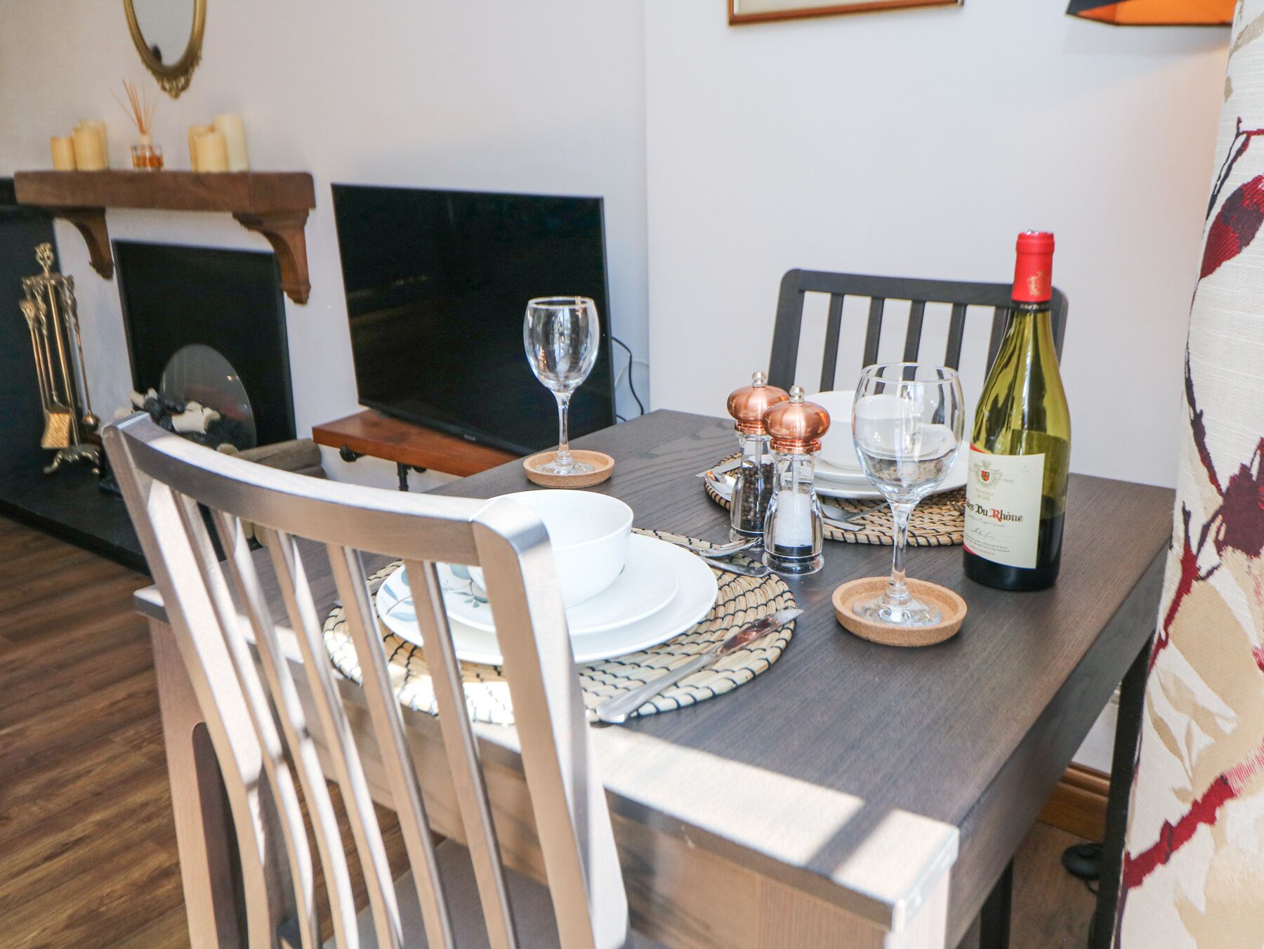 A dining table set with plates, glasses, and a bottle of wine.