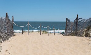 A sandy beach with a wooden fence and rope barrier leading to the ocean. - Atlantic Coast Inn (Fenwick Island)