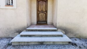 A wooden door with a decorative panel, a small window with a metal grille, and a concrete staircase leading to the door.