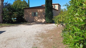A rustic house with a gravel driveway, surrounded by trees and greenery.