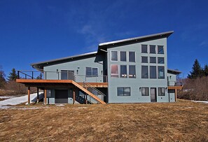 A modern two-story house with a flat roof, large windows, and a covered outdoor area. - Great Alaska Get Away (Homer)