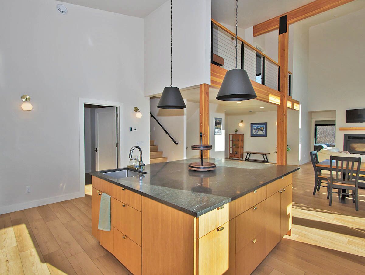 Une cuisine spacieuse dotée d’un grand îlot central, de meubles en bois et d’un luminaire suspendu moderne.