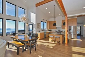 A spacious kitchen with wooden cabinets, a central island, and a large window overlooking a scenic view. - Great Alaska Get Away (Homer)