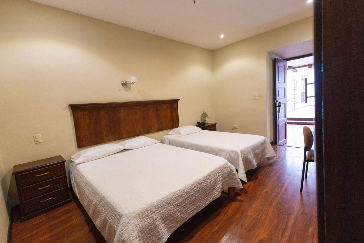 A hotel room with two beds, a wooden dresser, a nightstand, and a chair.