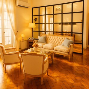 A living room with a sofa, chairs, a coffee table, and a radiator.