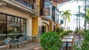 An outdoor café with tables and chairs, a gelateria, and a sign for Dolce Vita. - Del Mar Condo w/ Ocean and Golf Views (Playa Herradura)