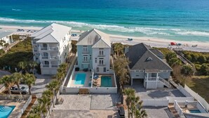 Une propriété située en bord de mer, dotée d’une piscine, de plusieurs bâtiments et offrant une vue sur la plage.