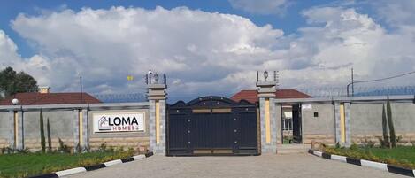 Una entrada con reja a una propiedad, con un letrero que dice "LOMA HOMES".