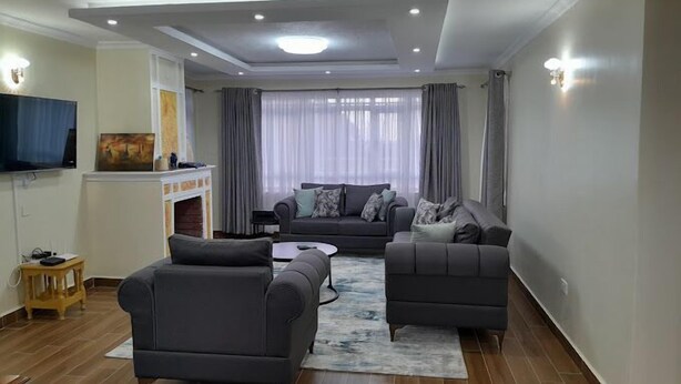 Un salon moderne avec un canapé gris, une table basse et un téléviseur à écran plat fixé au mur.