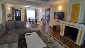 Un salon moderne avec un canapé, une table basse, une cheminée et un téléviseur.